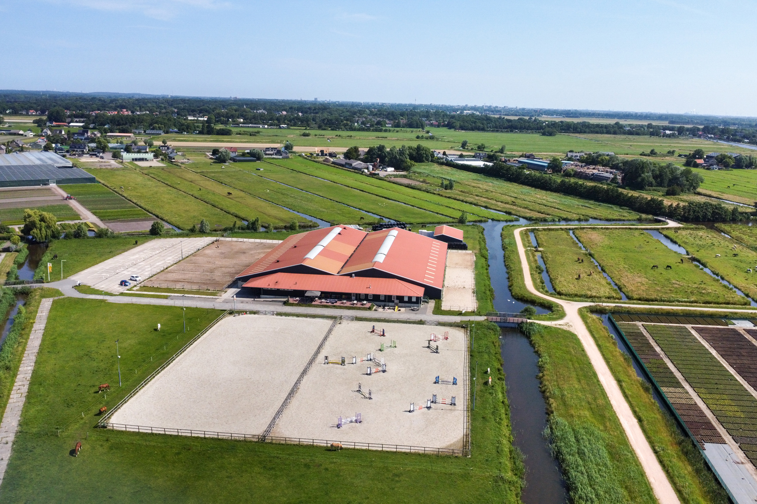 van manege met grote binnenhal, buitenrijbanen en weilanden met paarden aan de Amperestraat 8d in Hillegom.